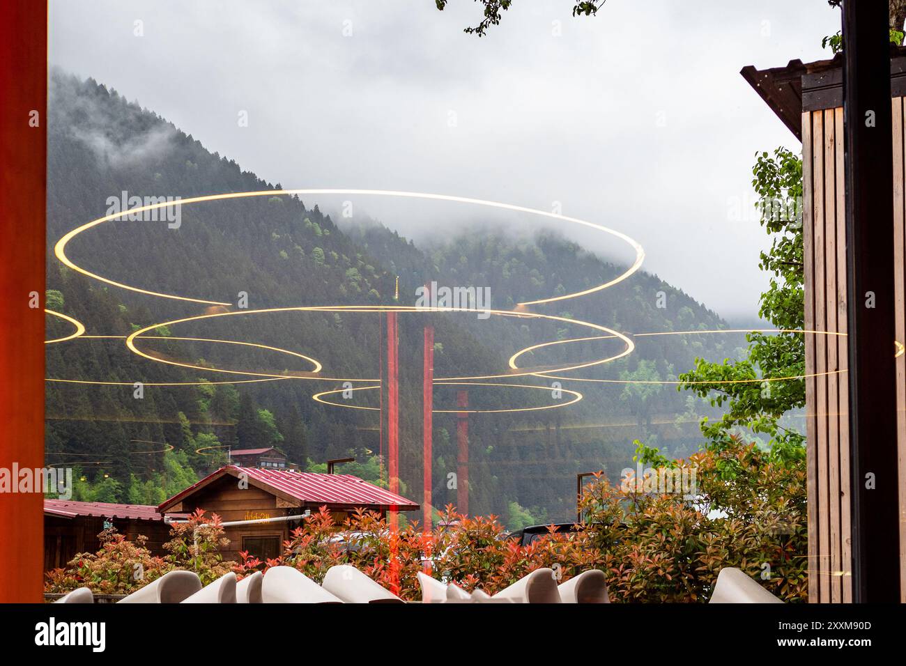 Reflexionen von Lampen in Glasfenstern und grauen Wolken auf den Bergen im Hintergrund am Sommertag in Uzungol Dorf am Ufer des Usungol See in C Stockfoto