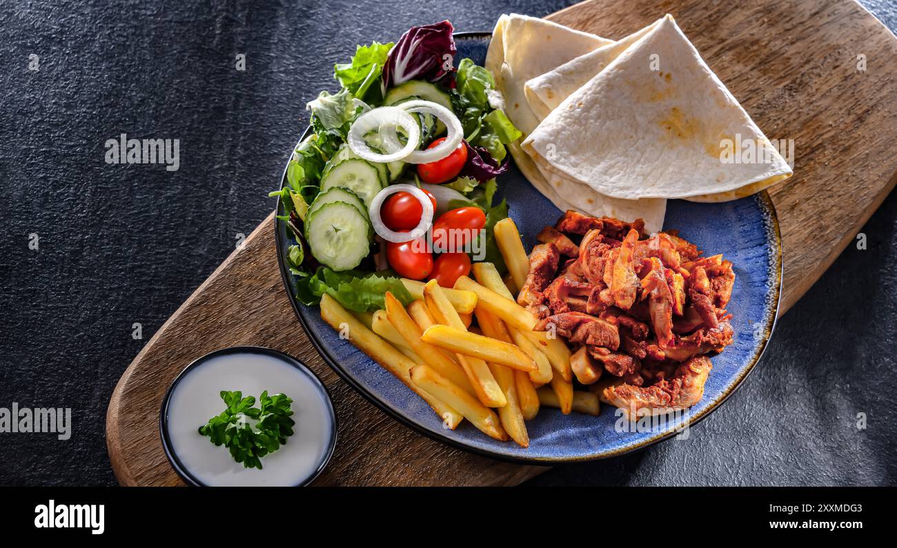Kebab serviert mit Pommes frites, Pitta-Brot, Gemüse und Tzatziki Stockfoto