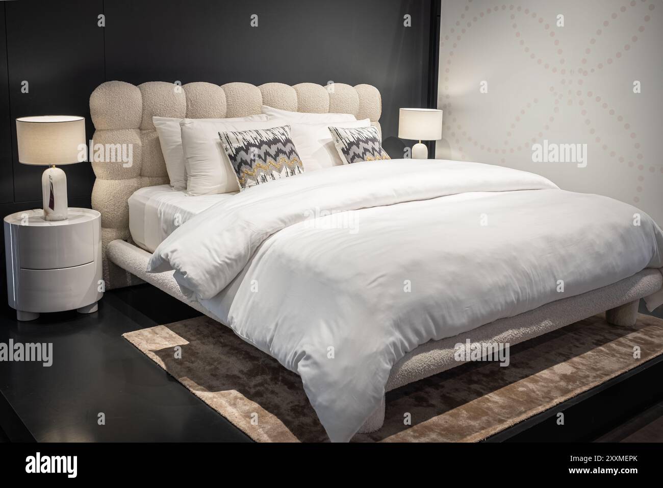 Stilvolles Schlafzimmer mit Doppelbett. Moderne Schlafzimmereinrichtung mit einem Hauptbett mit zwei Nachttischlampen. Großes, komfortables Doppelbett in eleganter Atmosphäre Stockfoto