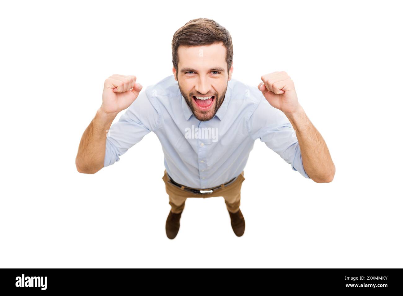 Sieger im Alltag. Blick von oben auf einen glücklichen jungen Mann, der Positivität und Gesten ausdrückt, während er isoliert auf weißem Hintergrund steht Stockfoto