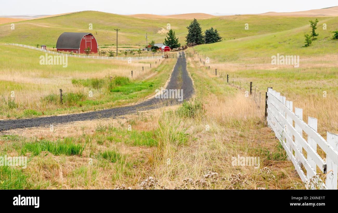 Er führt zu einer Idaho-Farm, die Kies in die rote Scheune gelesen hat Stockfoto