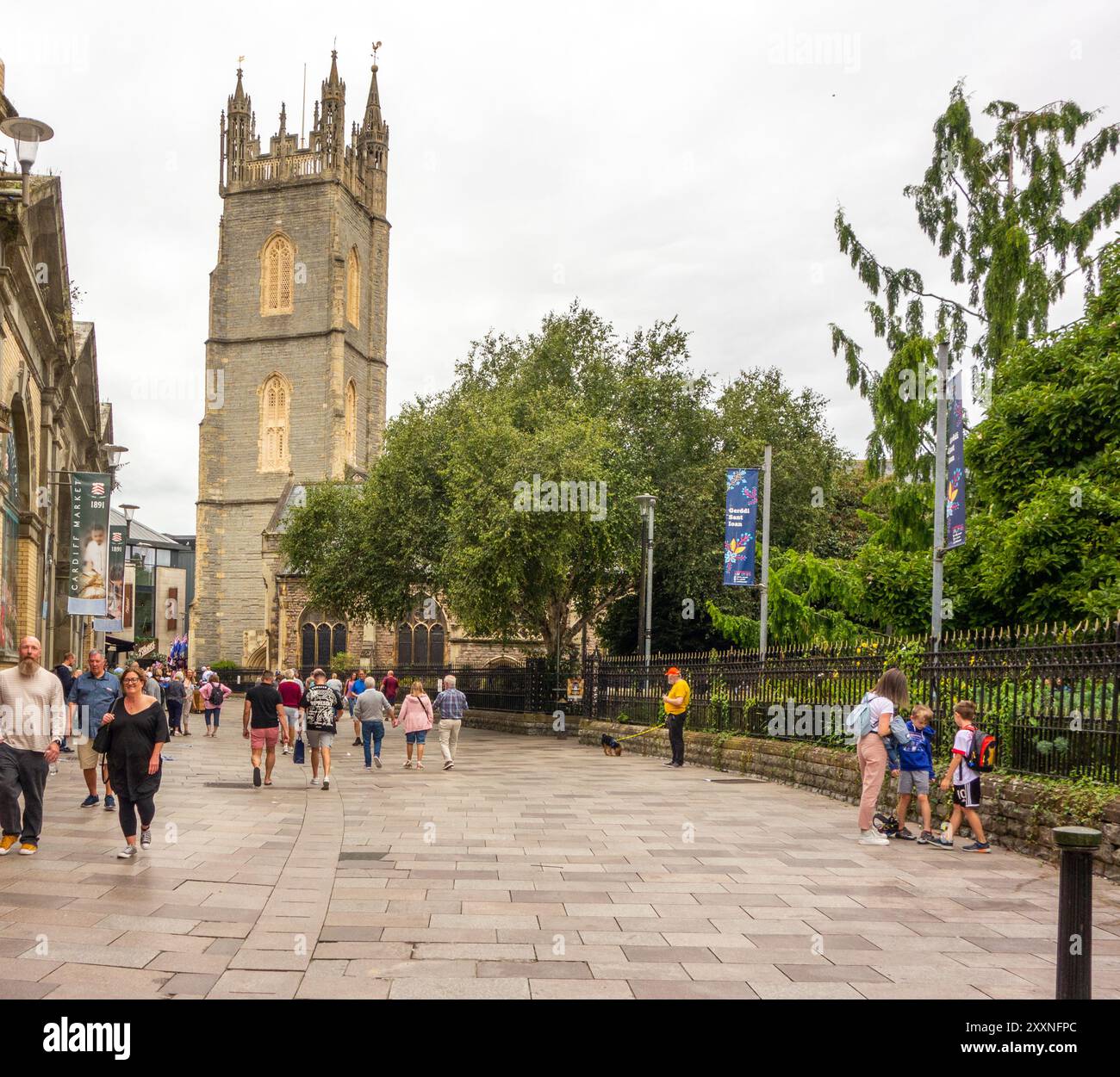 Einkaufsmöglichkeiten und Touristen entlang der Trinity Street in der walisischen Hauptstadt Cardiff mit Blick auf die St. John the Baptist City Parish Church. Stockfoto