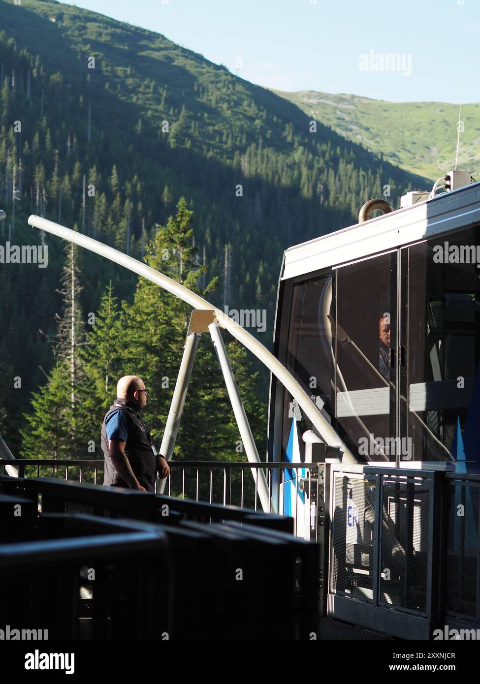 Kasprowy Wierch, Polen - 27. Juli 2024: Ein Seilbahnbetreiber steht in der Nähe der Seilbahnstation mit einer riesigen und atemberaubenden Bergkulisse Stockfoto