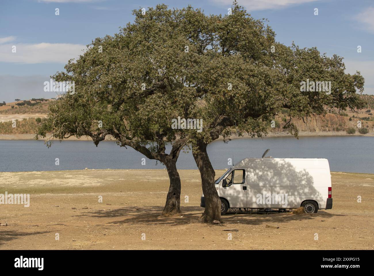 Wohnmobil auf einer Alentejo Staumauer Landschaft mit dem See hinter und unter dem Schatten eines Baumes, in Portugal Stockfoto