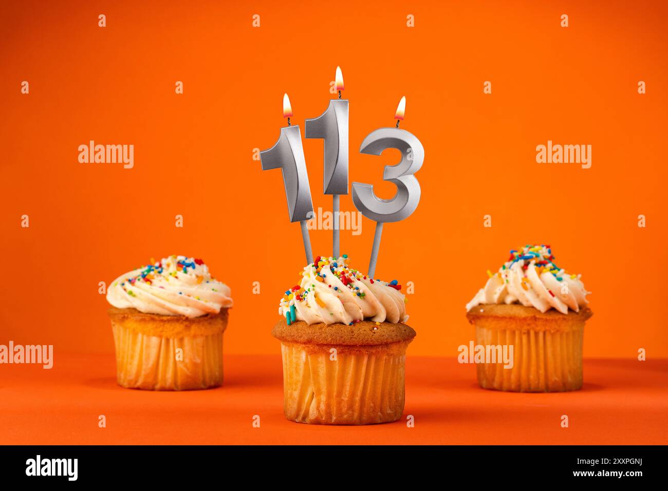 Kerze Nummer 113 - Feier mit Geburtstagskuchen auf orangem Hintergrund Stockfoto