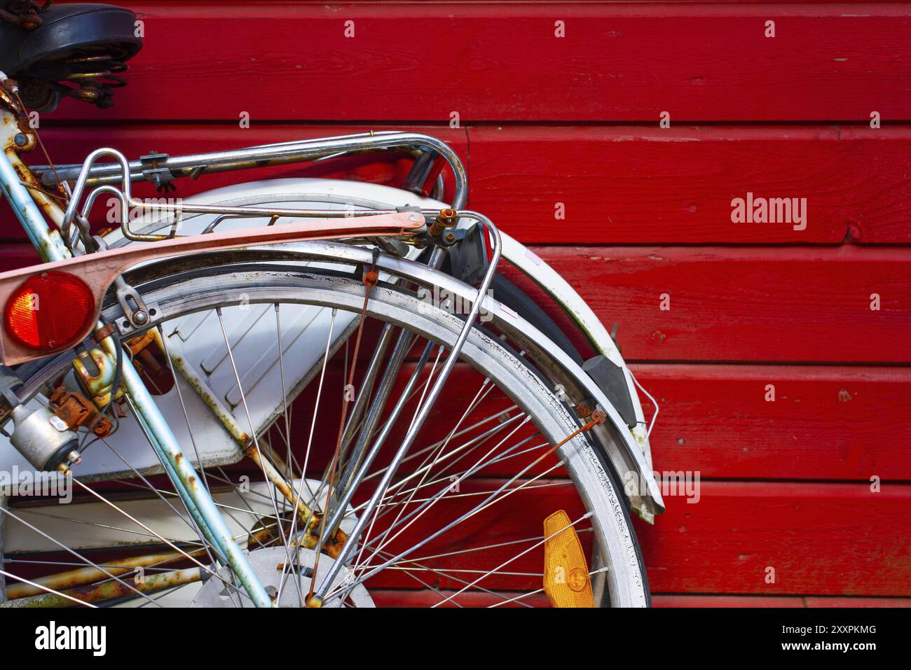 Zwei alte Fahrräder, die sich an eine rote Holzwand lehnen Stockfoto