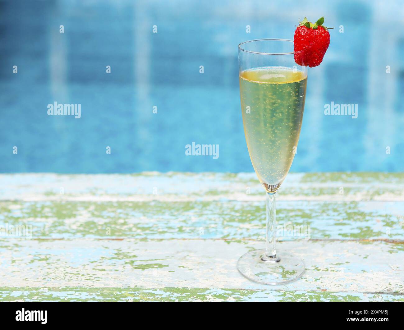 Glas Champagner mit Erdbeeren auf blauem Hintergrund Sommer-Pool-party Stockfoto