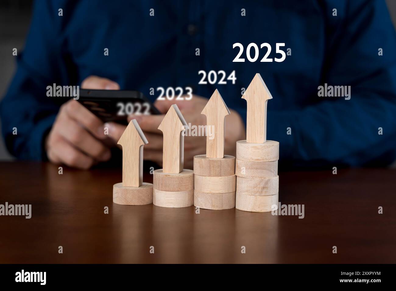 Geschäftsmann mit Smartphone, der auf steigende Pfeildiagramme zeigt, zukünftige Geschäftsziele des Unternehmens im Jahr 2025, Planung und Strategie, Geschäftsentwicklung Stockfoto