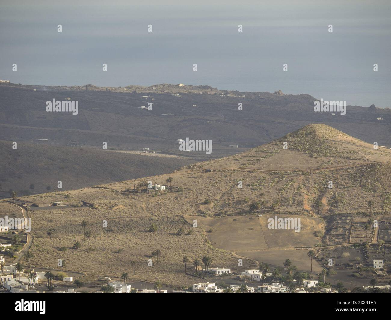 Meerblick über eine karge hügelige Landschaft und ein Dorf mit verstreuten Häusern, lanzarote, Kanarische Inseln, Spanien, Europa Stockfoto