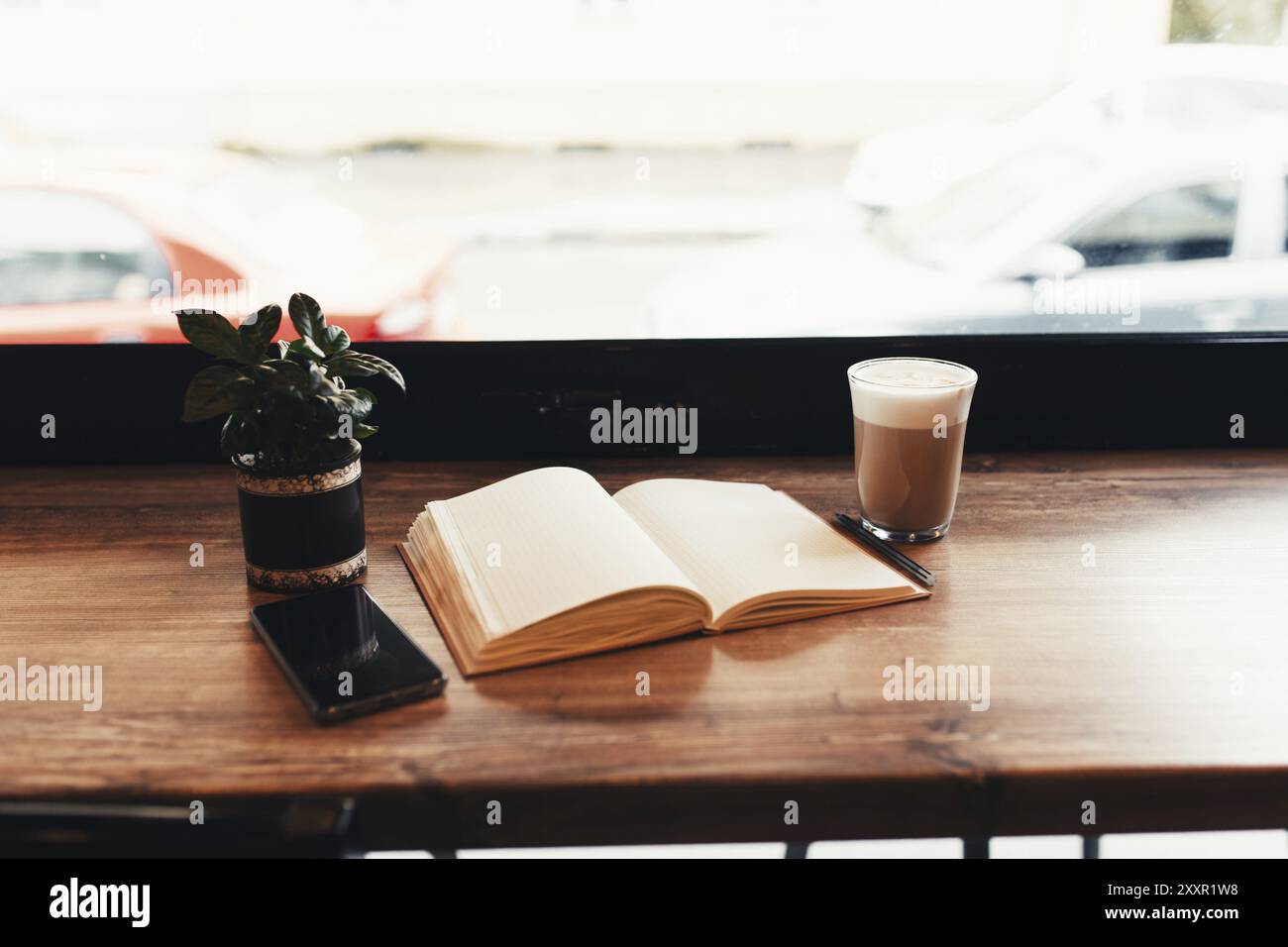 Tasse Kaffee, Notizbuch, Telefon am Tisch im Café. Unscharfer Hintergrund. Stockfoto