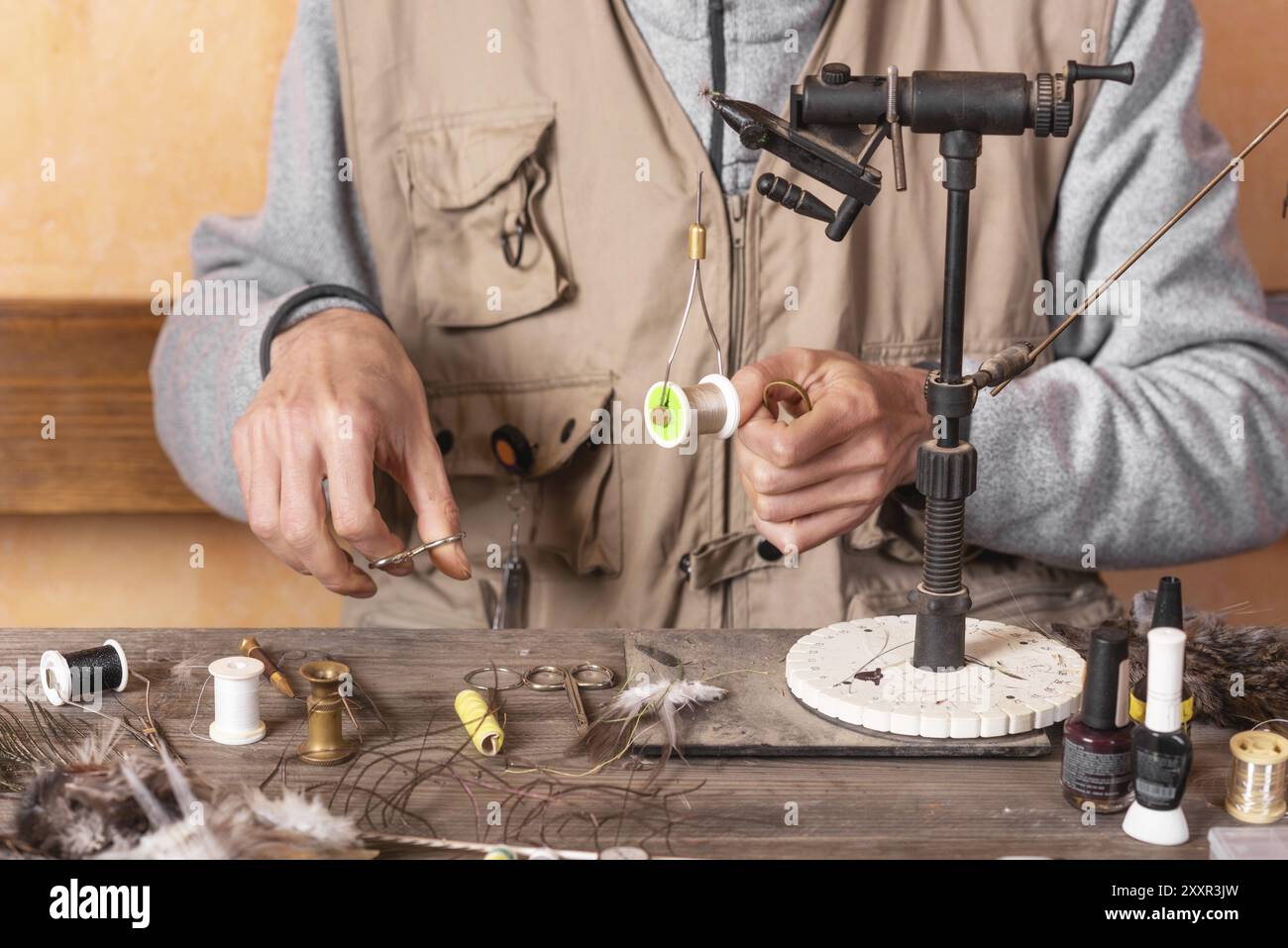 Mann macht Forellenfliegen. Fliegenbindeausrüstung und Material für die Vorbereitung des Fliegenfischens Stockfoto