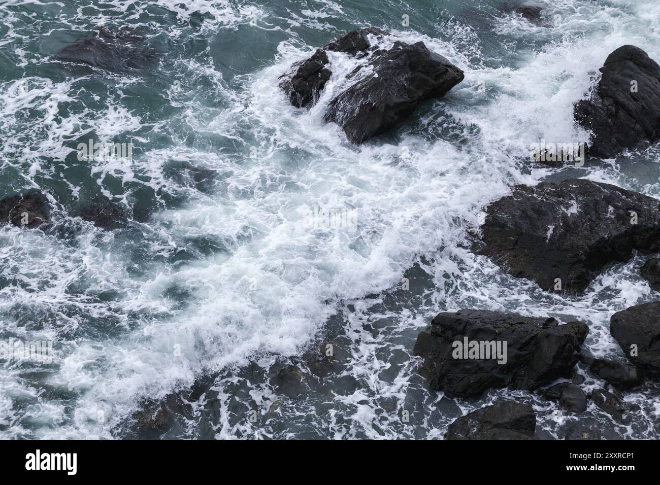 Schwarze Küstenfelsen und Uferwasser, aus der Vogelperspektive. Dongbaek Park von Busan City, Südkorea Stockfoto