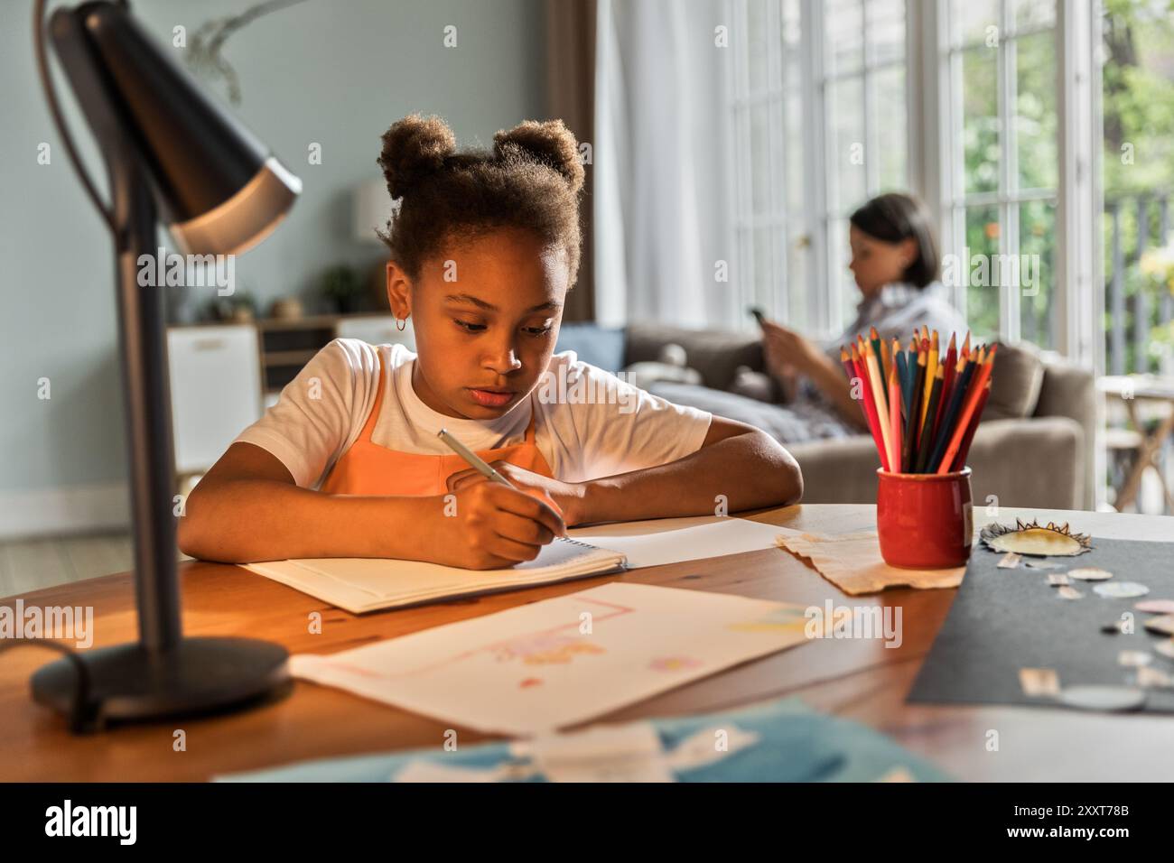 Afroamerikanisches Mädchen, das Hausaufgaben macht oder zeichnet Stockfoto