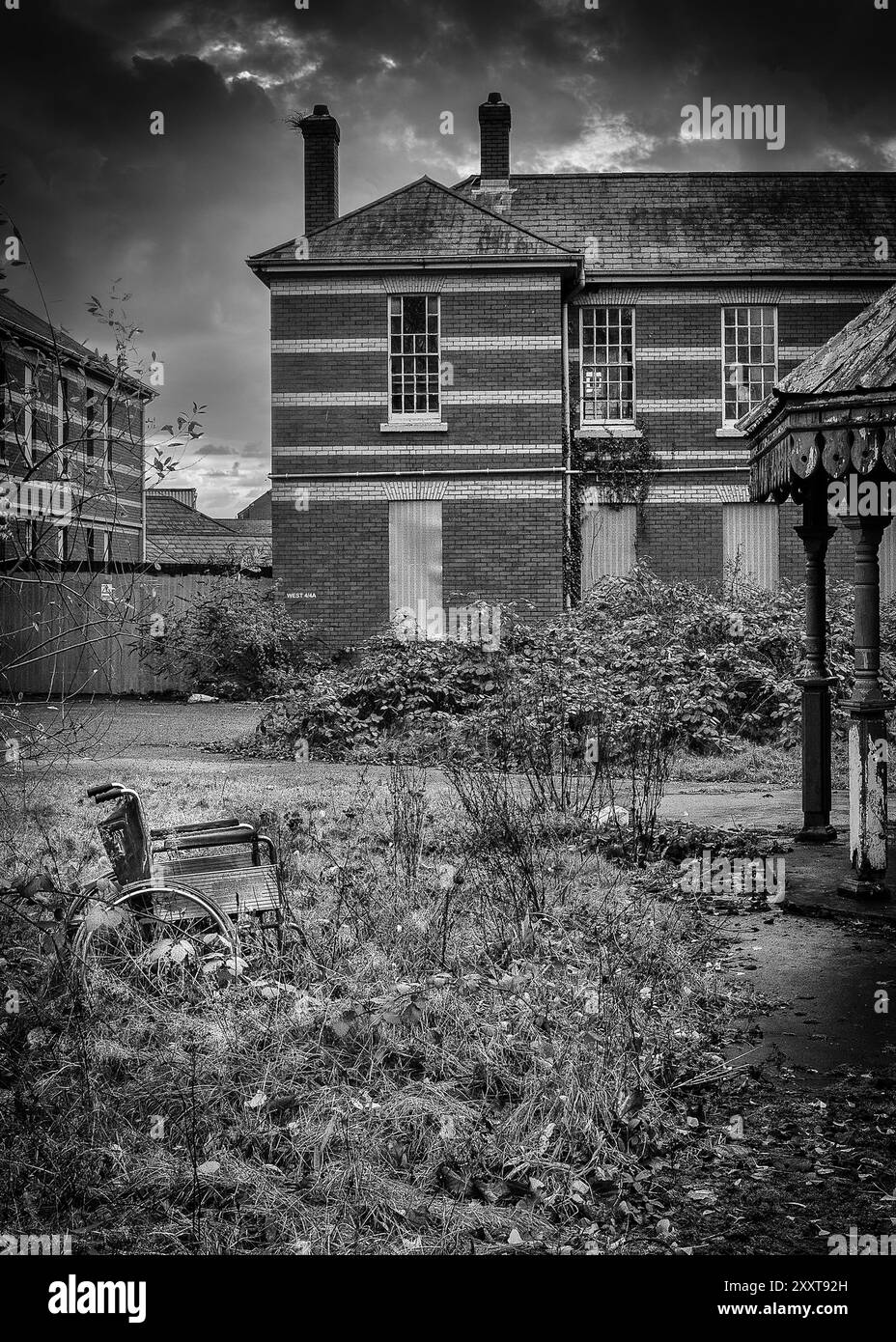 Verlassener Rollstuhl vor einem leeren NHS-psychiatrischen Krankenhaus in Cardiff, Wales. Concept NHS, UK Health Services, UK Mental Health. Schwarzweißbild. Stockfoto