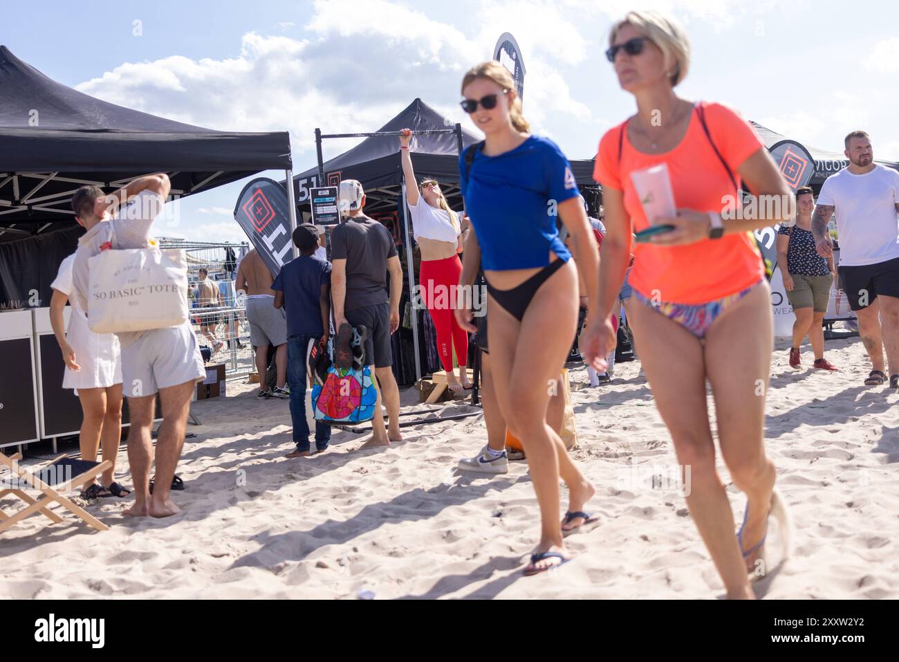 Warnemünde - Battle The Beach 2024 Warnemünde, Deutschland 24. August 2024: Eine sportliche Frau testet ein zu Werbezwecken ausgestelltes Sportgerät und macht Klimmzüge während der Battle the Beach 2024 am Strand von Warnemünde. Battle the Beach, größtes Functional Fitness Event Deutschland, findet vom 23.08.24 bis 25.08.24 statt. Mecklenburg-Vorpommern Stockfoto