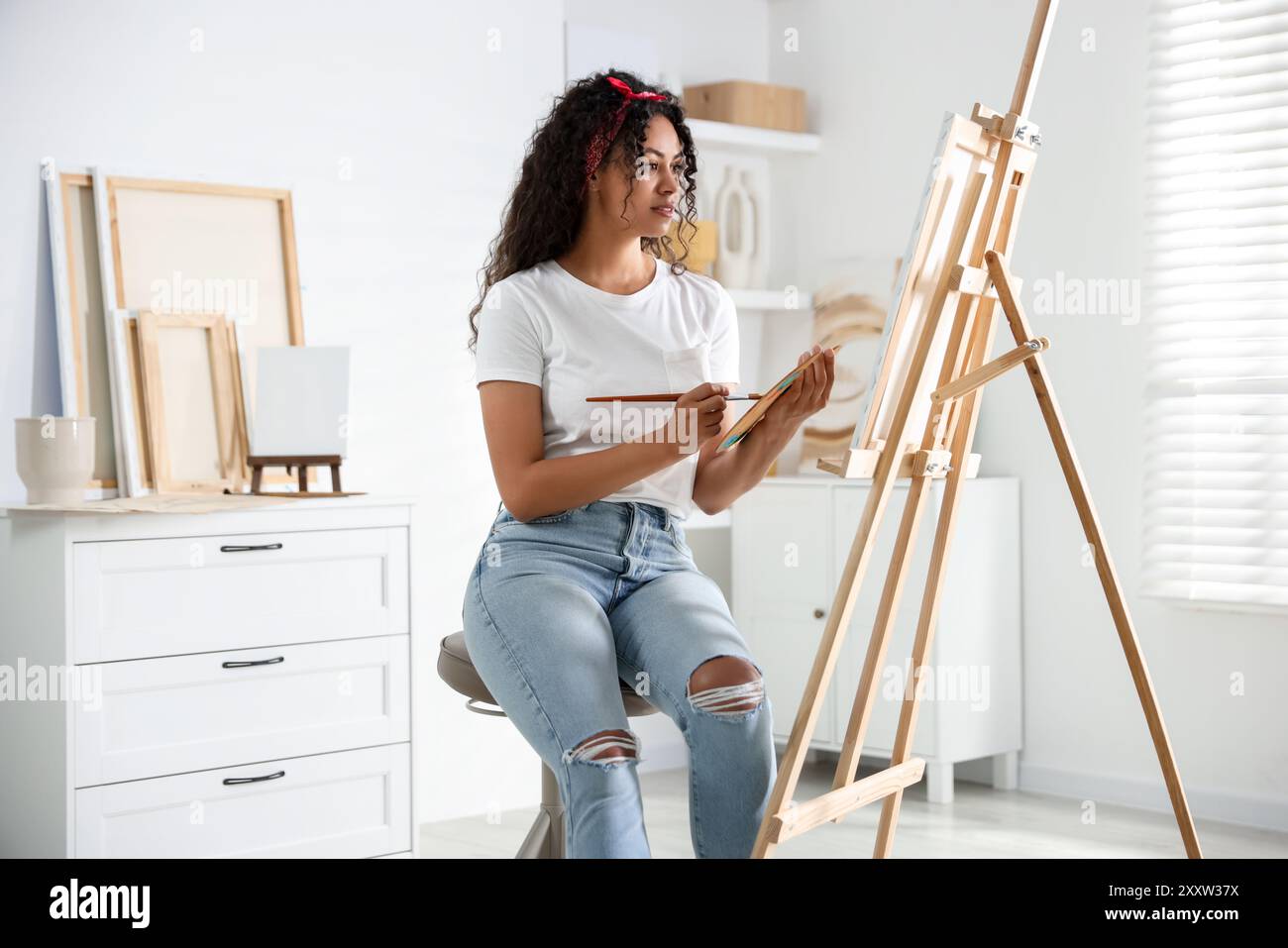 Schöne Frau, die im Studio ein Bild auf Leinwand zeichnet Stockfoto