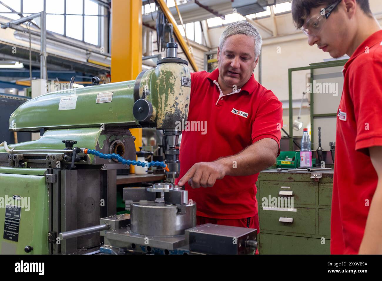 Ranstadt, Deutschland. August 2024. Jonas helle (r), ausgebildeter Bediener von Schneidemaschinen, erhält bei der Hassia Verpackungsmaschinen GmbH von Trainer Christian Seum, ebenfalls Teamleiter Produktion, Einweisung in eine konventionelle Fräsmaschine. Der Maschinenbauspezialist baut Umformmaschinen, Füll- und Dichtmaschinen und sucht Nachwuchstalente. Quelle: Christian Lademann/dpa/Alamy Live News Stockfoto