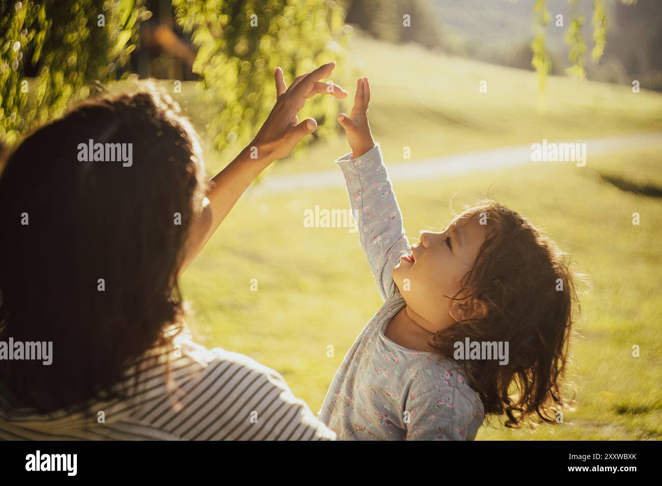 Idyllische Aufnahme von Mutter und Tochter, die zusammen bei Sonnenuntergang in der Natur mit Sonnenlicht spielen. Nahaufnahme mit Bokeh und Vintage-Kinoobjektiv. Konzept Stockfoto