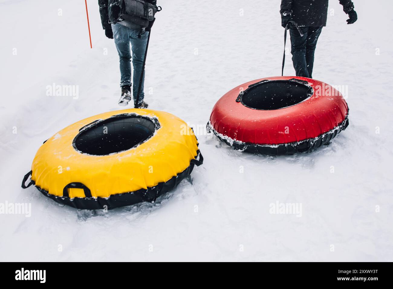 Zwei Personen ziehen Innenrohre bergauf, um Schneeschuhlaufen zu betreiben Stockfoto