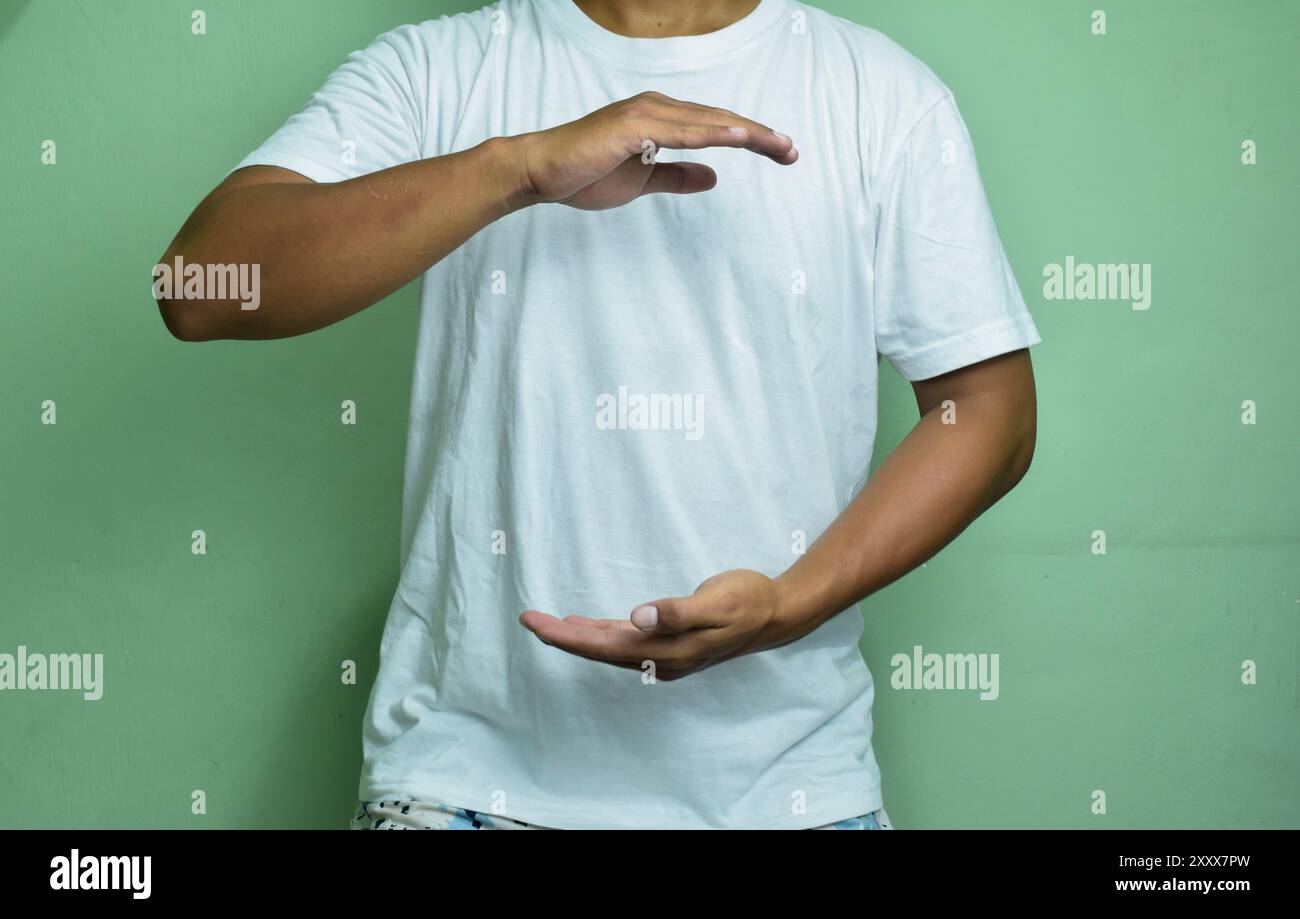 Mann, der Hände in der Nähe der Brust auf grünem Hintergrund hält Stockfoto