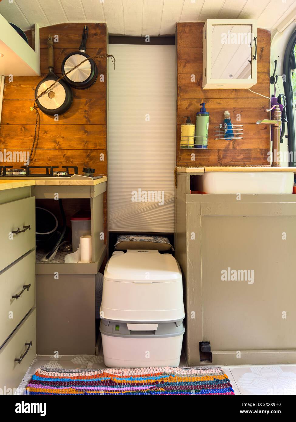 Innenansicht des Wohnmobils mit tragbarer Toilette, Waschbecken und Kochplatte. Stockfoto