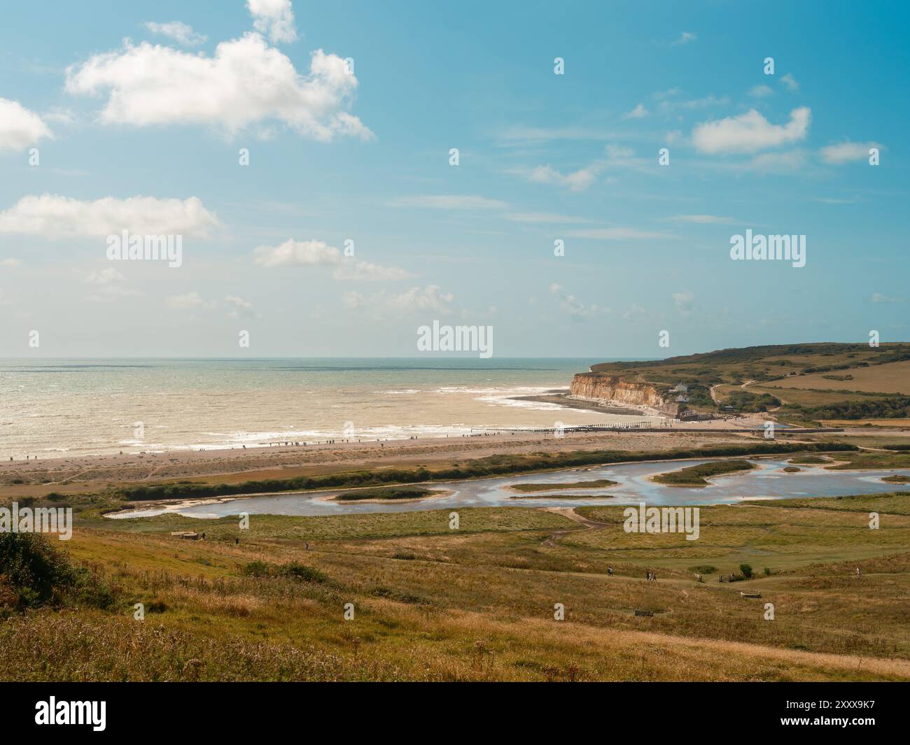 Seaford - Eastbourne - Großbritannien - 2024.08.25: Atemberaubendes Bild von weißen Kreidefelsen vor einem blauen Himmel, mit Wellen, die sanft entlang der Sieben Schwester krachen Stockfoto