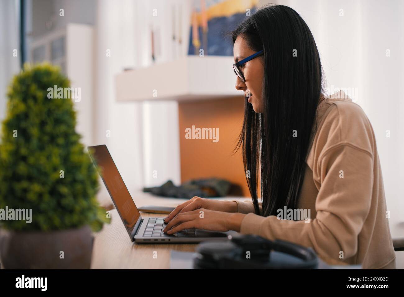 Asiatische junge Frau mit Brille, die mit einem Laptop arbeitet, einen Modellbildschirm und Hände bei der Arbeit mit digitaler Technologie. Verwenden eines Laptop-Arbeitsplatzes Seitenansicht Stockfoto