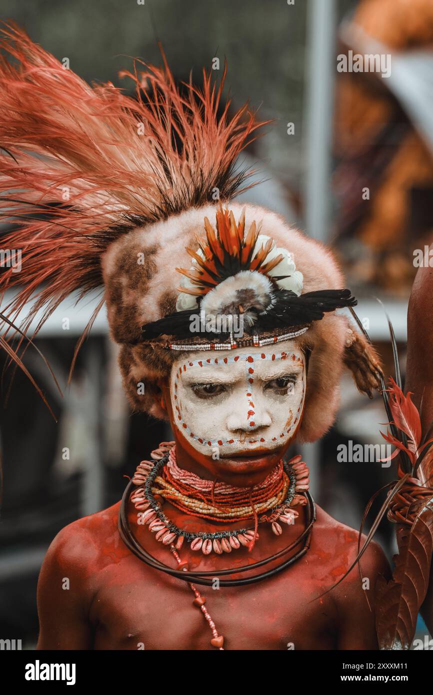 Ein Mann aus der Provinz Hela, Papua-Neuguinea, mit lebendiger Gesichtsfarbe und einem auffälligen Kopfschmuck mit Federn, der den Stolz der Stammesangehörigen symbolisiert. Stockfoto