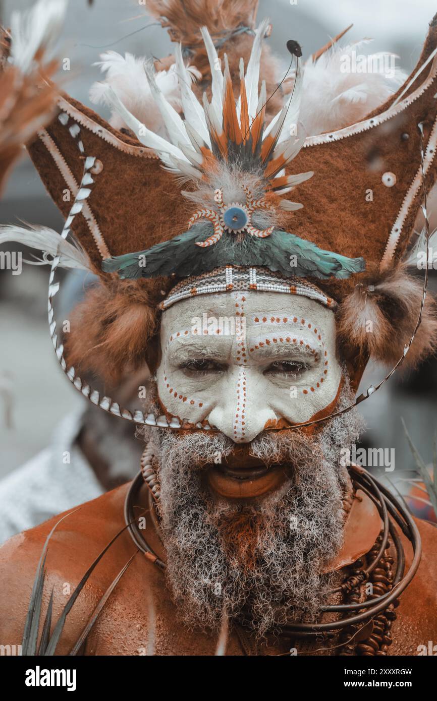 Ein Mann aus der Provinz Hela, Papua-Neuguinea, mit lebendiger Gesichtsfarbe und einem auffälligen Kopfschmuck mit Federn, der den Stolz der Stammesangehörigen symbolisiert. Stockfoto