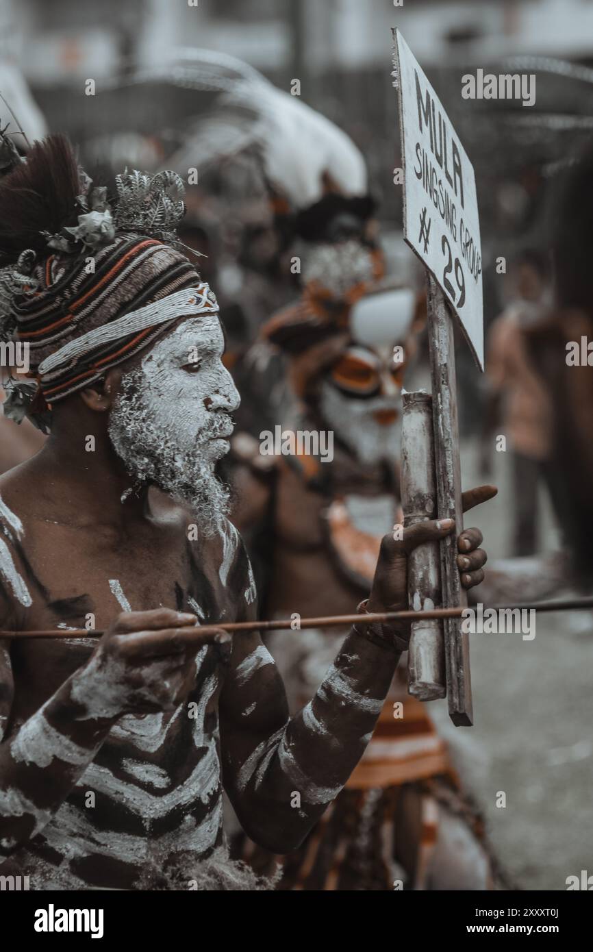 Ein Highlands-Krieger aus Papua-Neuguinea, der in traditioneller Kleidung mit komplizierter Gesichtsfarbe und Kopfschmuck verziert ist, strahlt Kraft und kulturellen Stolz aus. Stockfoto