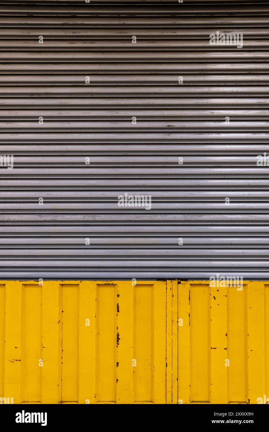 Vertikales altes und verwittertes Wellblech Garage- und Ladentür mit gelbem Rand Stockfoto