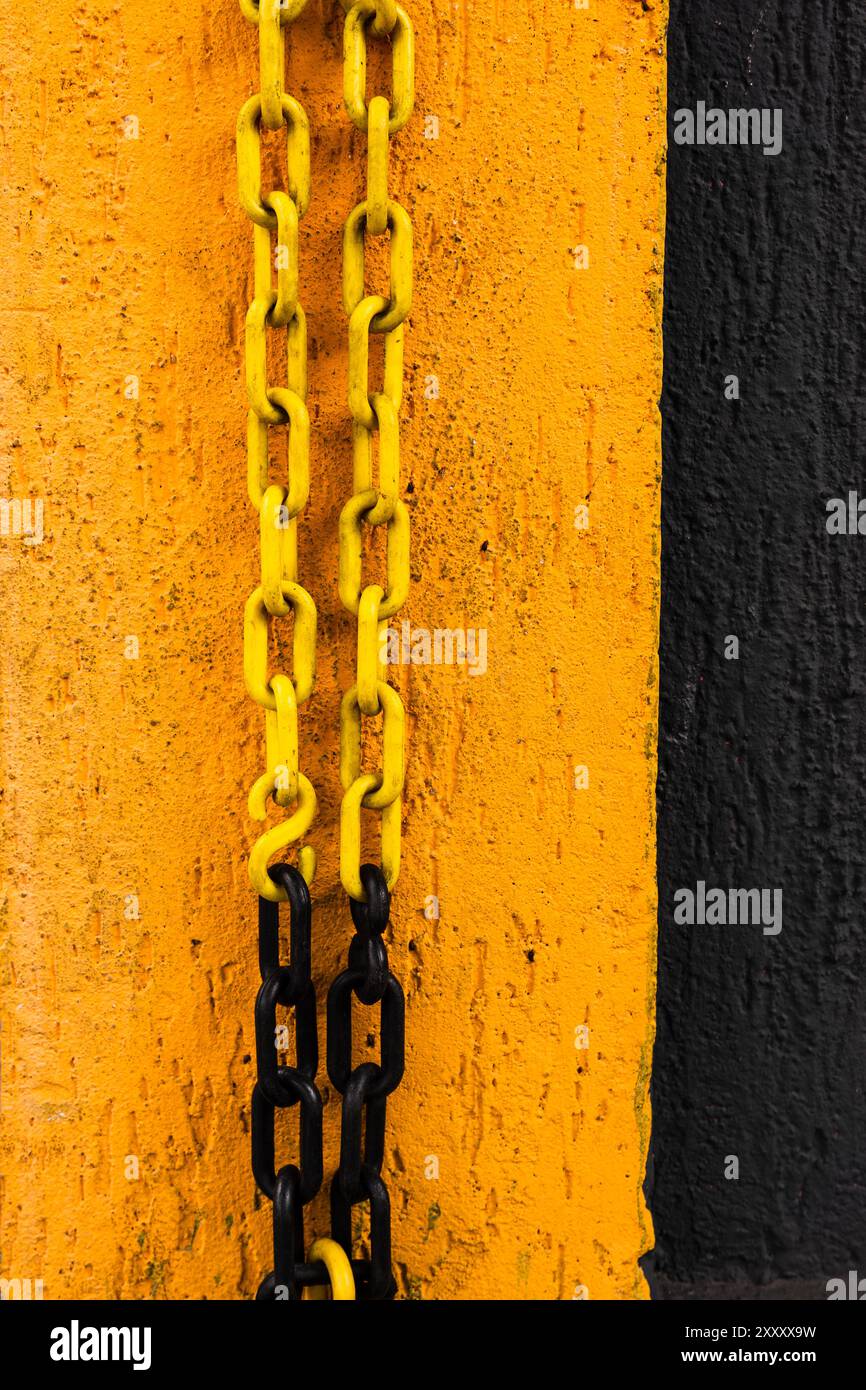 Gelbe und schwarze Kette hängt an einer gelb-schwarzen Wand. Stockfoto