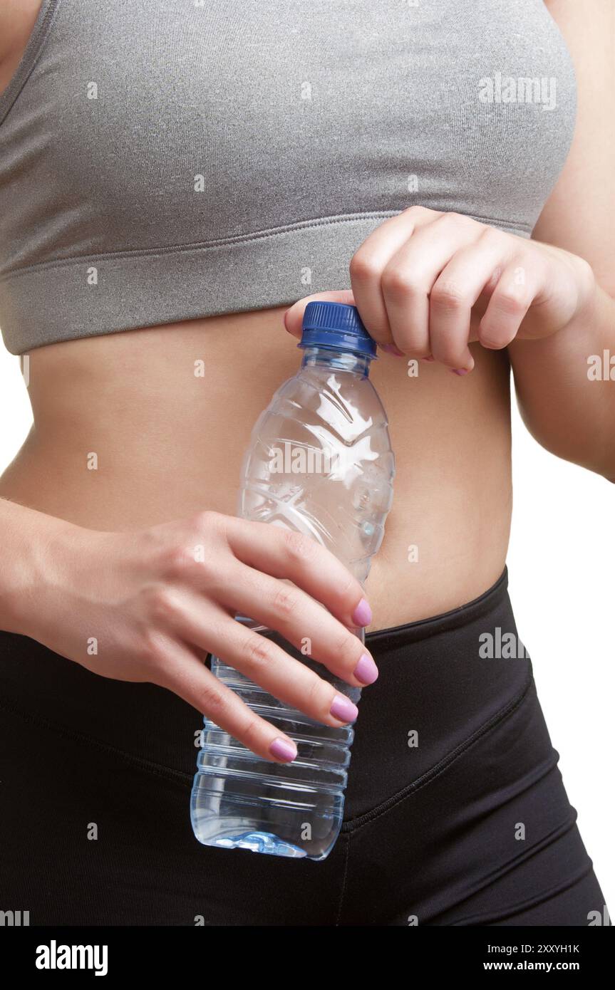 Frau mit einer Plastikflasche Wasser, gekleidet in Sportkleidung, isoliert in weiß Stockfoto