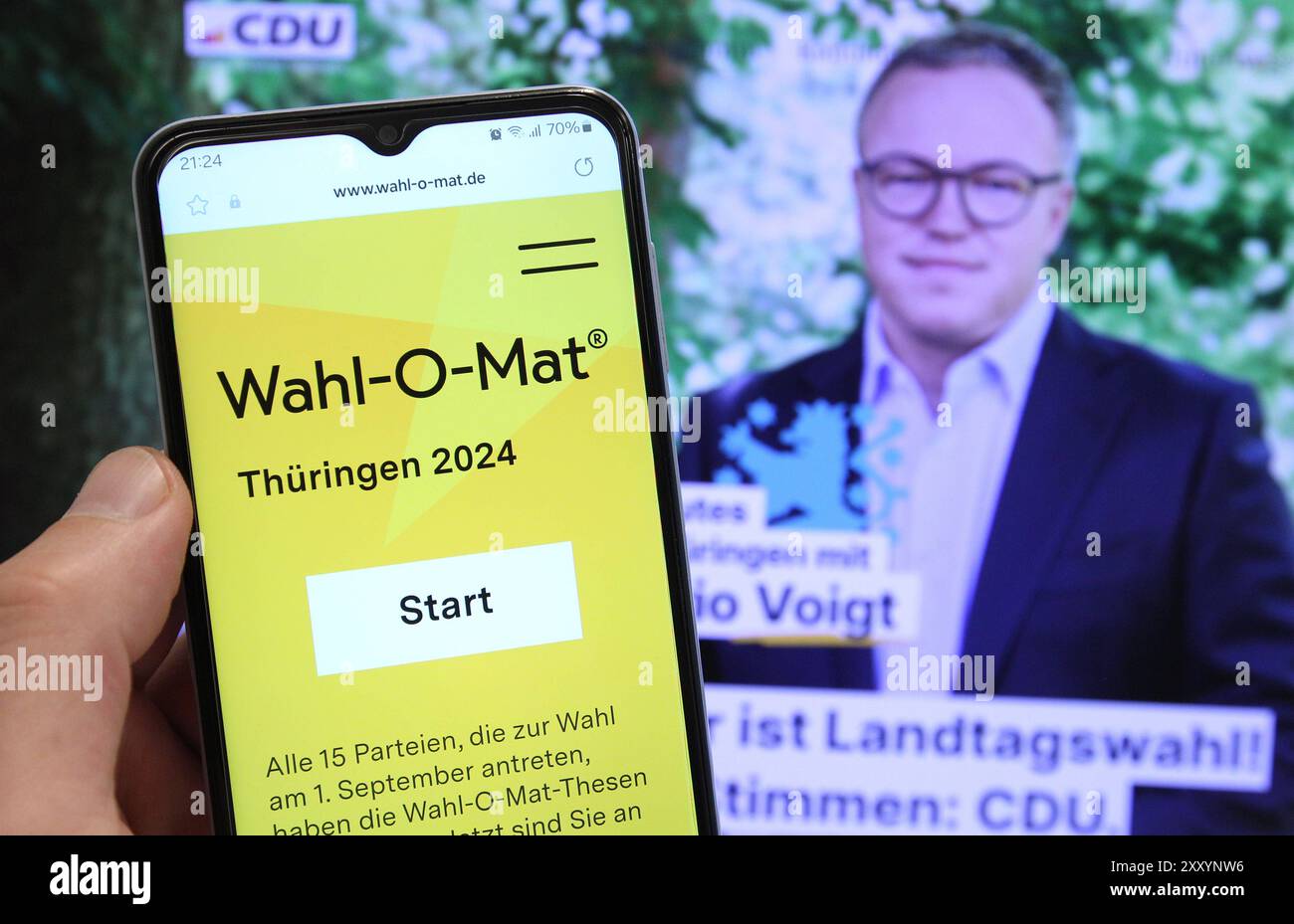 Auf einem Smartphone war der Wahl-O-Mat für die Landtagswahl in Thüringen geöffnet. Dahinter ist auf einem Bildschirm der Spitzenkandidat der CDU für die Wahl, Mario Voigt, zu sehen. Schnelsen Hamburg *** die Wahl O Mat für die Landtagswahl in Thüringen wurde auf einem Smartphone dahinter geöffnet, der CDU-Spitzenkandidat Mario Voigt ist auf einem Bildschirm Schnelsen Hamburg zu sehen Stockfoto