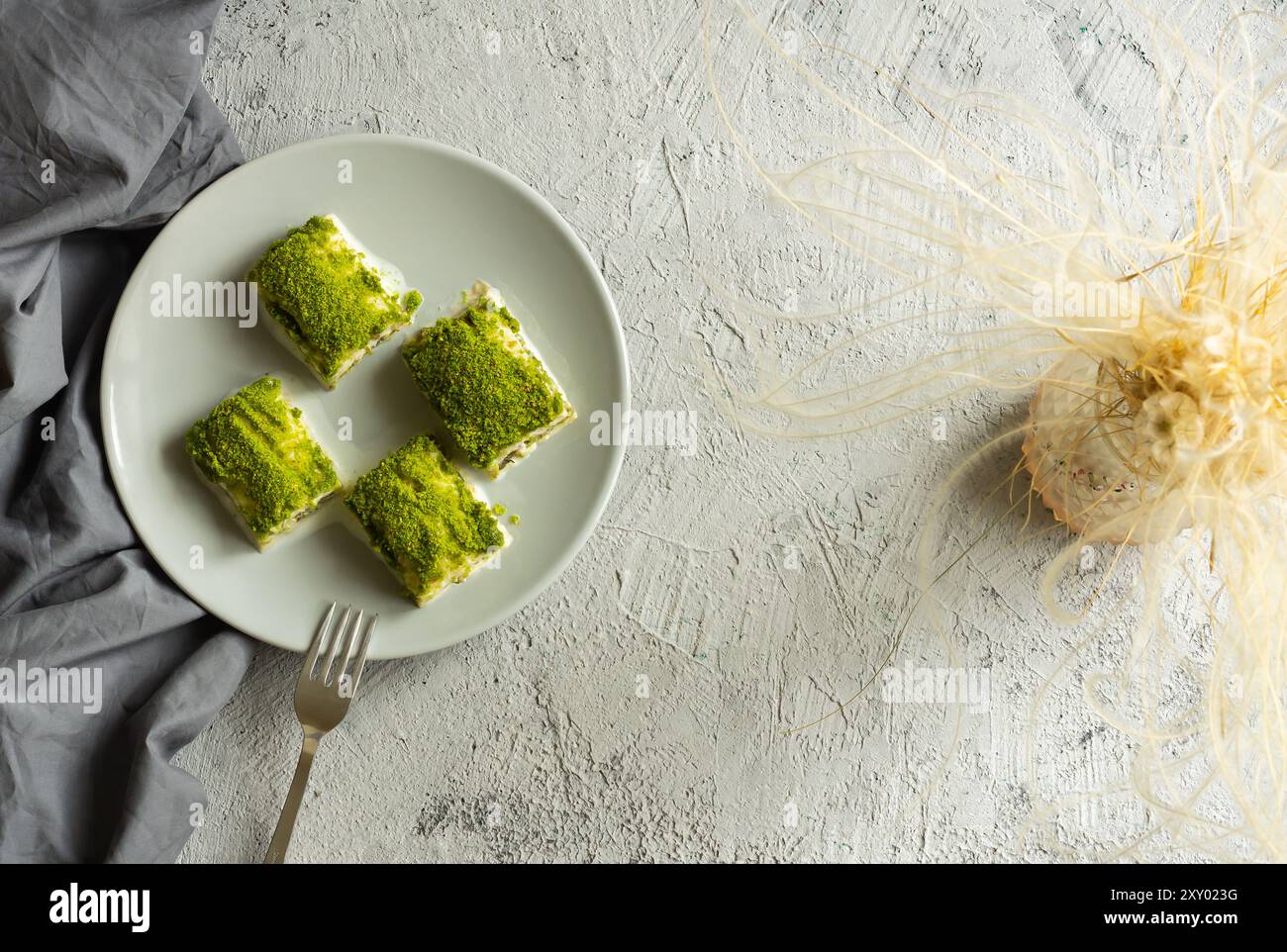 Traditionelles türkisches neues Dessert kalte Milchbaklava mit Pistazien auf weißem rustikalem Tisch, ramadan- oder Urlaubsdesserts-Konzept Stockfoto