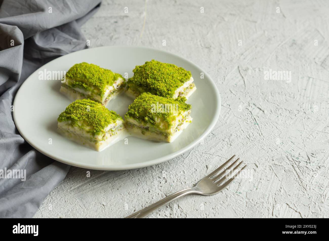 Traditionelles türkisches neues Dessert kalte Milchbaklava mit Pistazien auf weißem rustikalem Tisch, ramadan- oder Urlaubsdesserts-Konzept Stockfoto