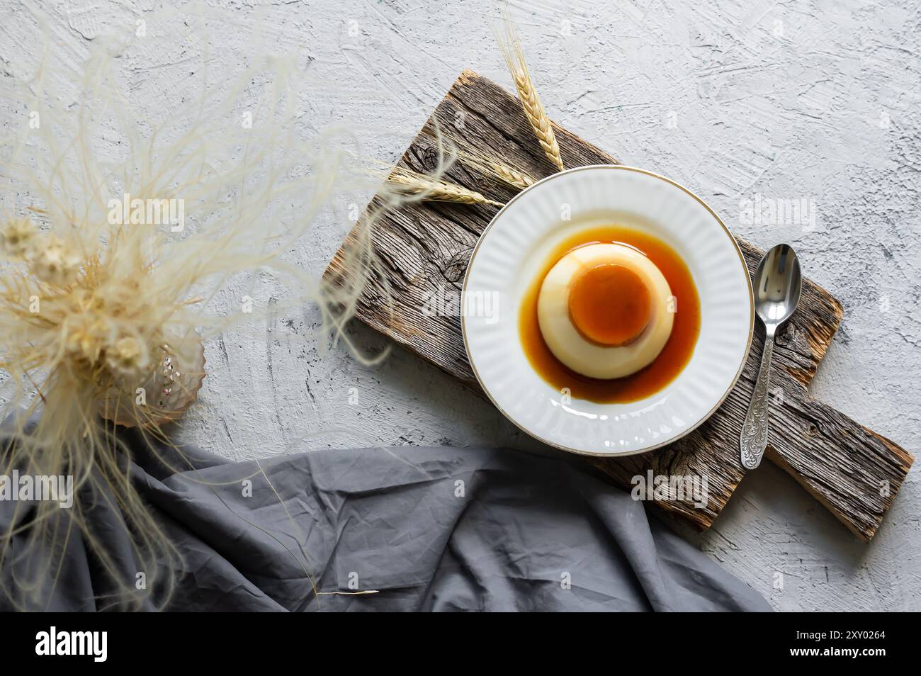 Cremiger Karamellpudding mit Karamellsauce auf Teller auf weißem rustikalem Tisch Stockfoto