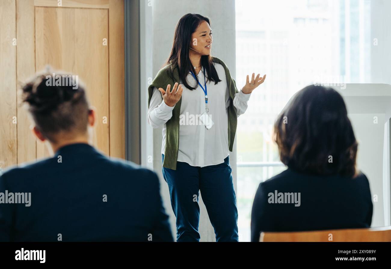 Professionelle Frau, die in einer Geschäftswerkstatt spricht, spricht Kollegen an. Ansprechende Schulung mit Schwerpunkt auf der beruflichen Entwicklung. Stockfoto