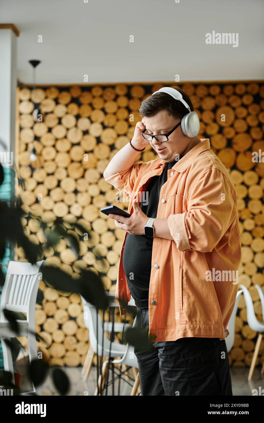 Ein Mann mit Down-Syndrom hört Musik über Kopfhörer, während er in einem Café steht. Stockfoto