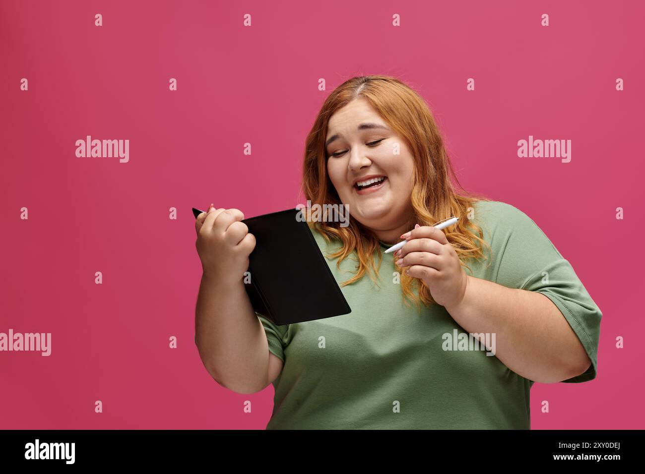 Eine Frau lacht, während sie eine Tablette und einen Stift benutzt. Stockfoto