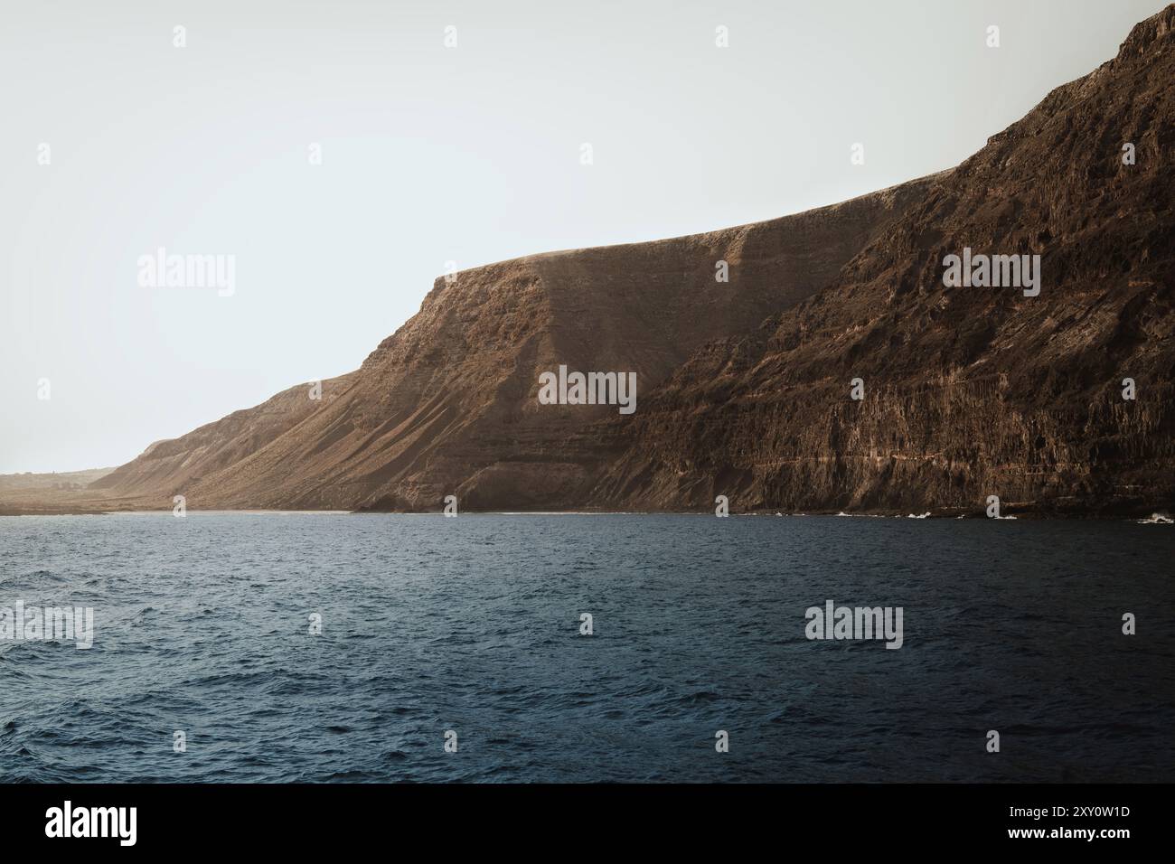 Dieses atemberaubende Bild zeigt die majestätischen Küstenklippen von Lanzarote auf den Kanarischen Inseln, die dramatisch aus dem Meer die natürliche Felsformation erheben Stockfoto