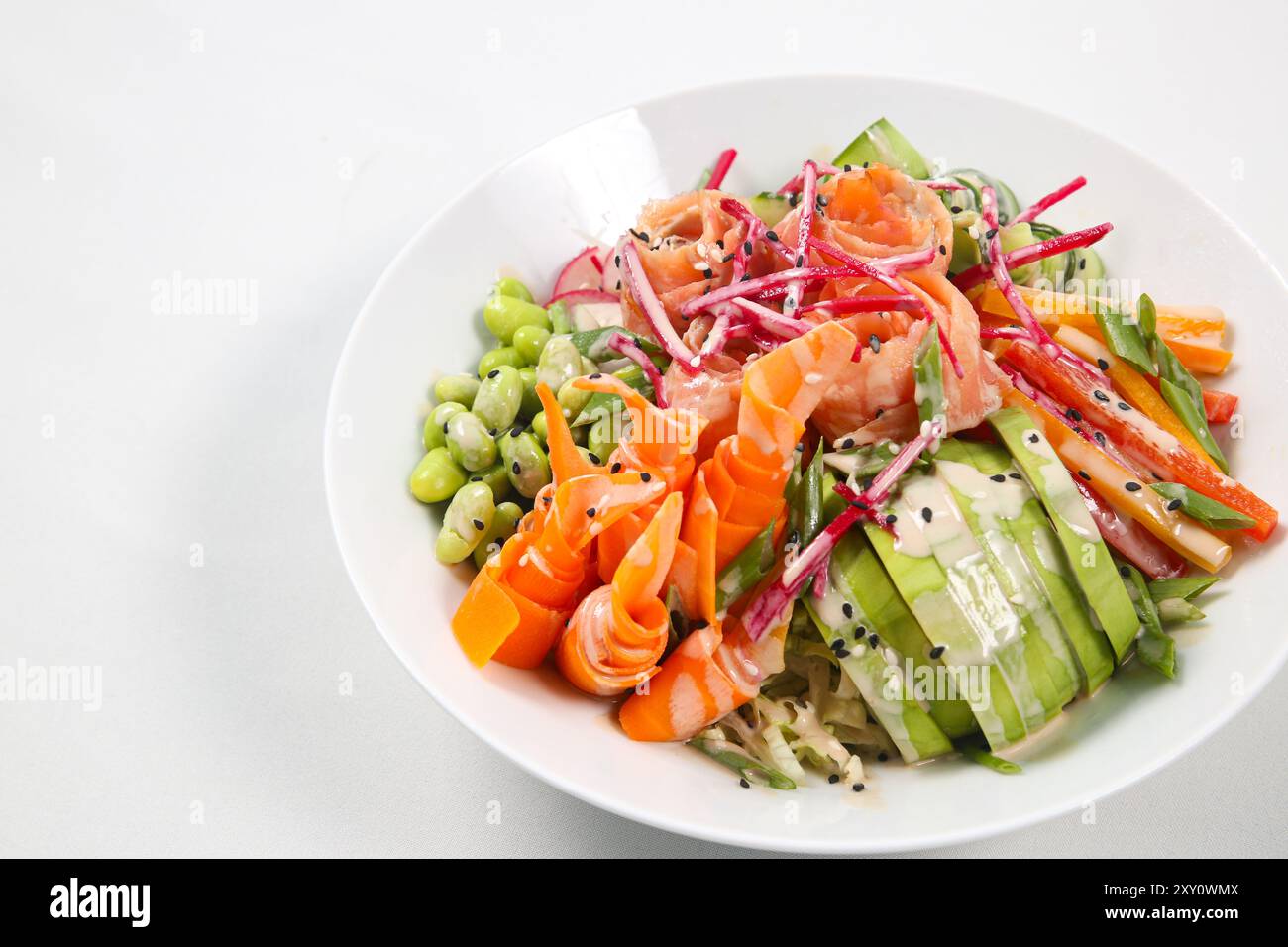 Rohe Bio Ahi Lachs Poke Bowl, Avocadorose, Rettich, Karotten, Gurken und grüner Salat, bestreut mit Frühlingszwiebeln und Sesamsamen Stockfoto