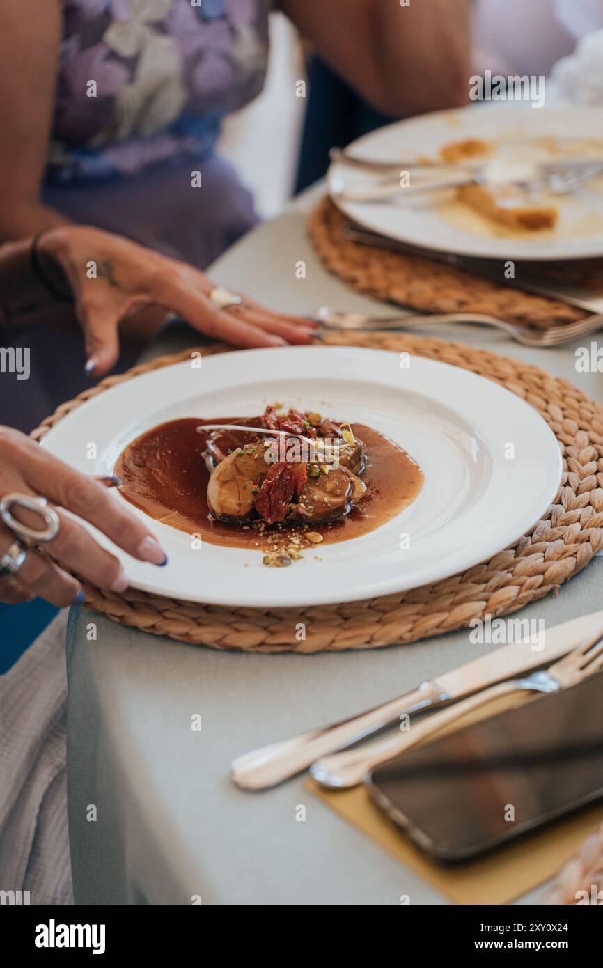 Eine wunderschön präsentierte Hochzeitstafel mit einem Gourmet-Gericht, serviert auf einem gewebten Tischset und umgeben von elegantem Besteck, was das Essen bereichert Stockfoto