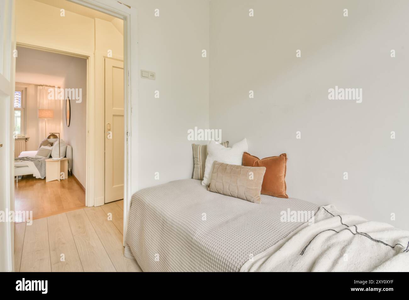Ein gut beleuchtetes, modernes Schlafzimmer mit minimalistischem Design, neutralen Farben, Linien und einfacher Einrichtung. Stockfoto