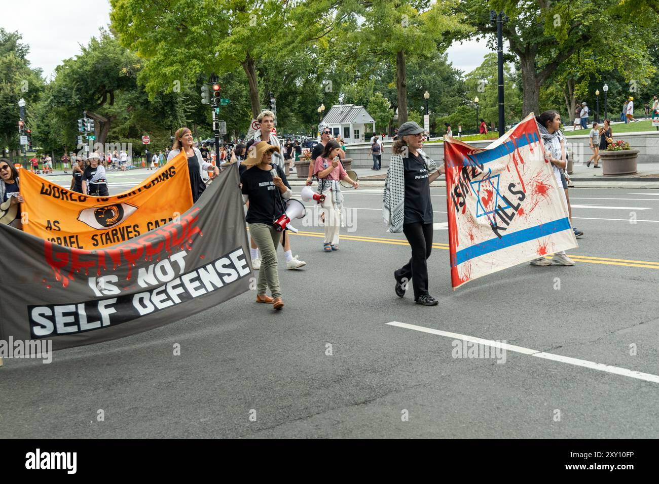 Washington DC, USA - 19.08.2024: Eine Gruppe von Menschen marschiert die Straße hinunter mit Schildern, auf denen steht: "Völkermord ist keine Selbstverteidigung." Stockfoto