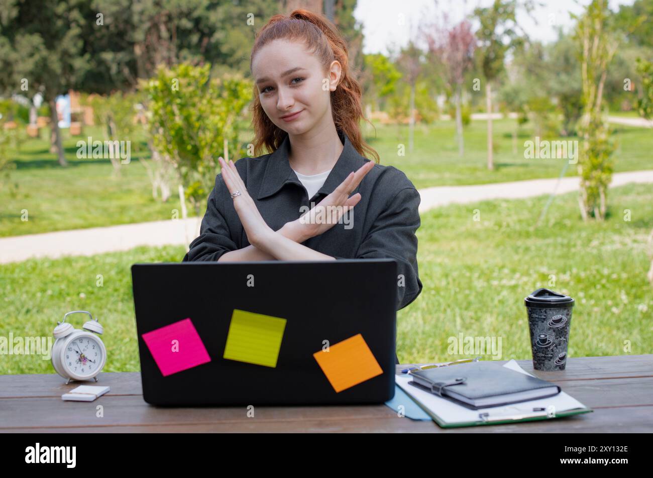 Ein Mädchen, das am Laptop arbeitet, Halt zeigt, draußen die Hände überquert. Stockfoto