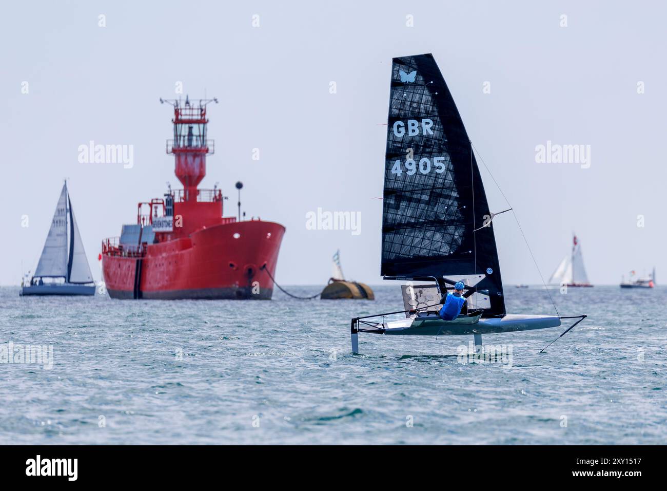 2024 International Moth UK National Championships. Das Schlauchboot mit Falter passiert vor dem Leuchtschiff Seven Stones, das in den Carick Roads verankert ist Stockfoto