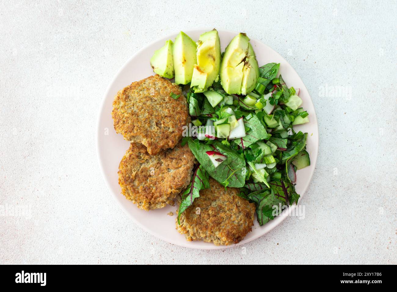 Quinoa-Schnitzel und gemischter Salat mit Avocado und Radieschen, Kiwi und Wasser mit Zitrone, köstliches herzhaftes Frühstück, veganer Lunch-Teller Stockfoto