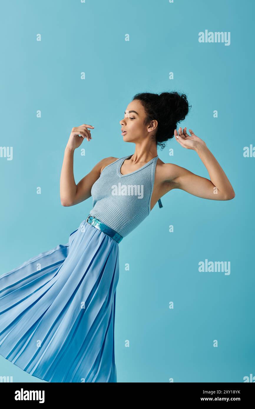 Eine junge Frau in einem blauen Kleid posiert vor einem leuchtend blauen Hintergrund. Stockfoto