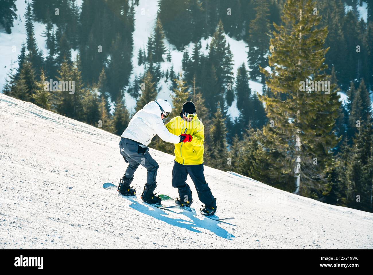 Goderdzi, Georgia - 13. januar 2023: Männliche Hipster-Instruktoren zeigen, wie man Snowboarder Balance hält Anfänger Snowboarder bergab auf weiß Stockfoto